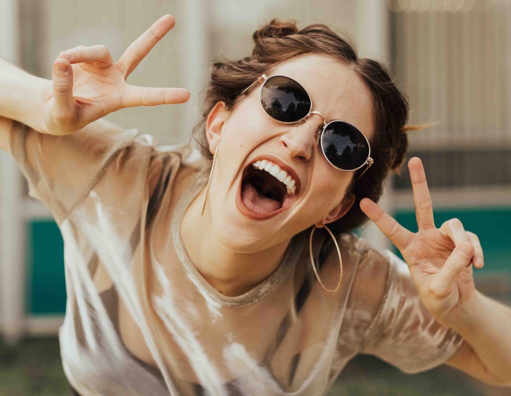 Photo of happy woman flashing peace hand gestures. Photo by Brooke Cagle/Unsplash